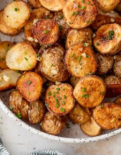 Golden roasted potato halves with garlic notes and caramelized edges. Garnished with fresh chopped herbs and served right from the oven to enjoy its crispiness.