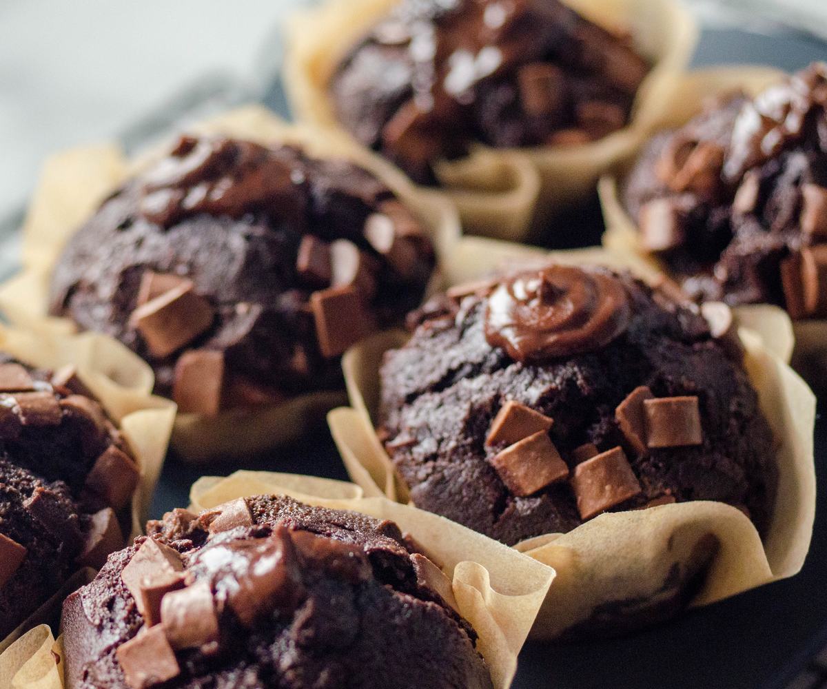 Freshly baked dark chocolate jumbo muffins, topped with glossy ganache and chocolate chunks.