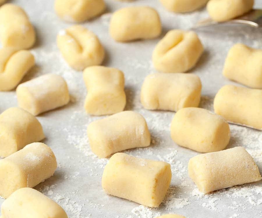 Light, tender ricotta gnocchi made from simple ingredients, resting on a floured surface, ready for boiling