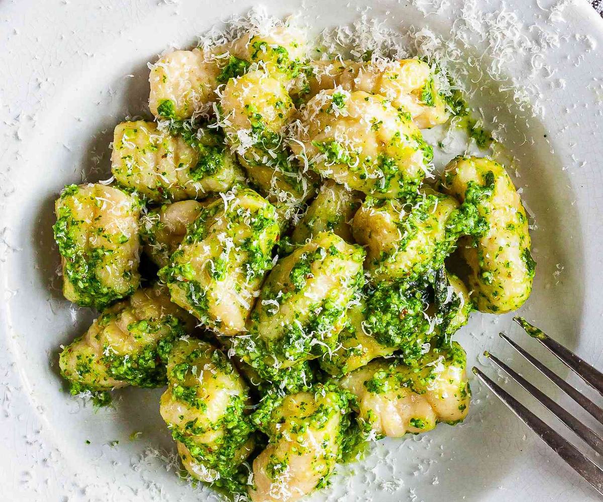 Freshly made parmesan ricotta gnocchi with drizzle of olive oil, tossed in basil pesto and with grated cheese on top.