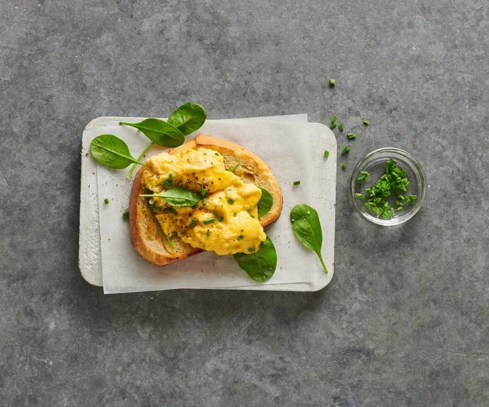 Toasted bread topped with fluffy scrambled eggs, fresh spinach, and chives — a simple, elegant breakfast idea.