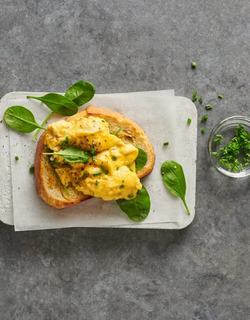 Toasted bread topped with fluffy scrambled eggs, fresh spinach, and chives — a simple, elegant breakfast idea.