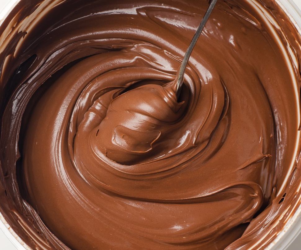 A bowl full of smooth, silky and glossy chocolate ganache, with a spoon creating swirls on the surface. Made for glazing, filling, piping and truffle making.